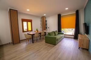 a living room with a green couch and a table at Chuspombo Apartamentos in Baralla