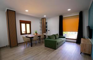 a living room with a table and a green couch at Chuspombo Apartamentos in Baralla