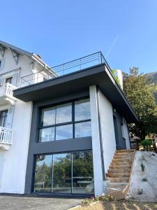 a white house with large windows and stairs at La Loge du Capitole in Veyrier-du-Lac