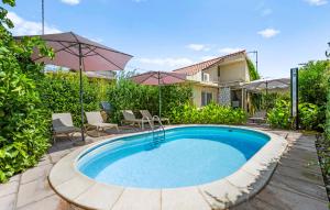a pool with chairs and umbrellas next to a house at Regina Apartments in Brodarica