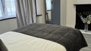 Una cama con una manta encima en un dormitorio. en 4 Bedroom House - Romford, en Dagenham 14 fotos más