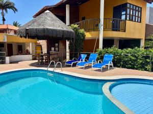 ein Pool mit blauen Stühlen und ein Haus in der Unterkunft Casa-Z pertinho do mar in Barra de São Miguel