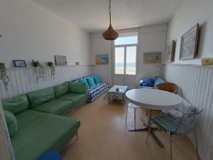 un soggiorno con un divano verde e un tavolo di appartement avec une superbe vue mer - 0014 a Soulac-sur-Mer