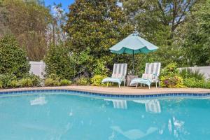 two chairs and an umbrella next to a swimming pool at The Pool Loft at Poplar Hill in Annapolis