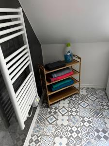Una habitación con un estante con toallas sobre un suelo de baldosas. en Le Quartier Blackforest-Straßburg, en Willstätt