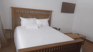 a large bed with white sheets and a wooden headboard at St Ives Unit 13, Uvongo Beach in Margate