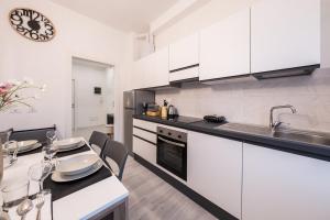 a kitchen with white cabinets and a table with chairs at 15 minuti a piedi dalla stazione centrale in La Spezia +14 photos