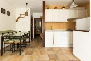 Una cocina con gabinetes blancos y una mesa con sillas. en Can Solsulet, en Es Pujols