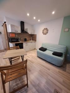 a living room with a blue bed and a table at L'Olivier in Saint-André-de-Sangonis