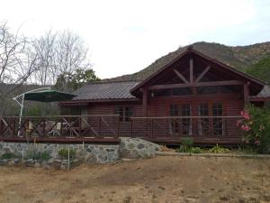 a log cabin with a deck and an umbrella at Cabañas Ocoa in Hijuelas