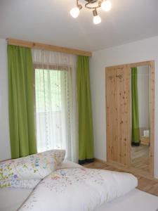 a bedroom with green curtains and a bed and a window at Pirchahof in Martello