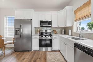 a kitchen with white cabinets and a stainless steel refrigerator at Fairway Cottage 2BR Retreat Near Sportsplex in Youngsville