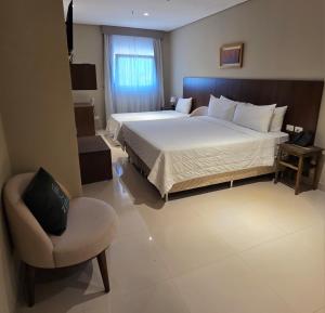 a bedroom with a large bed and a chair at Zielo Hotel in Asuncion