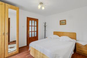 a bedroom with a white bed and a mirror at Pensiunea Valea Dornelor in Ortoaia