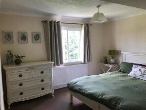 a bedroom with a bed with a dresser and a window at Rural farm stay with stunning indoor pool in Billingshurst +39 photos