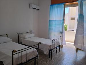 zwei Betten in einem Zimmer mit Fenster in der Unterkunft CarolHouse in Lido Conchiglia