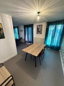 a dining room with a wooden table and blue curtains at Grand F3, proche gare Auxerre in Auxerre