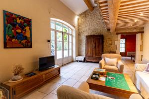Mas des Olivades - Ferme Provençale - Piscine في بيرنيه لو فونتينز: غرفة معيشة مع أريكة وتلفزيون