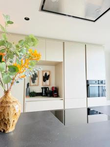 a kitchen with white cabinets and a vase with flowers at Cooth's Luxury Loft with City Views in Breda +10 photos