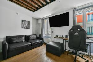 ein Wohnzimmer mit einem schwarzen Ledersofa und einem Schreibtisch in der Unterkunft Le Sorrento - 2 prs - Métro 12 - Proche Paris in Vanves + 3 Fotos