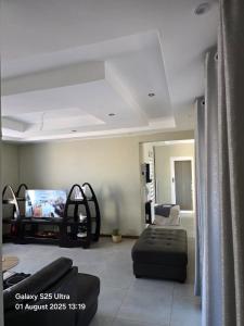 a living room with a couch and a tv at Lillies House in Mokoeng