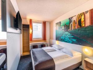 een slaapkamer met een bed en een schilderij aan de muur bij B&B Hotel Freiburg-Nord in Freiburg im Breisgau