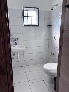 une salle de bains blanche avec toilettes et lavabo dans l'établissement Cozy Buxton, à Mombasa