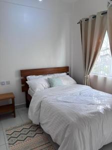 une chambre avec un lit blanc avec une fenêtre dans l'établissement Cozy Buxton, à Mombasa