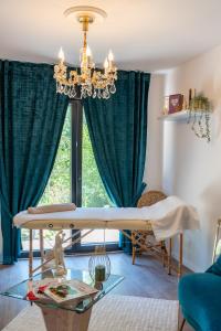 a living room with a table and a chandelier at Romance Me - Love Room Élégante avec Table de Massage & Pole Dance - Night & Day use in Évreux