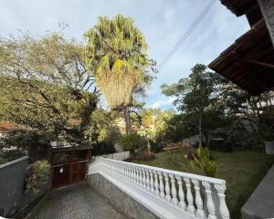 a white fence in a yard with a palm tree at Casa Klippel in Petrópolis