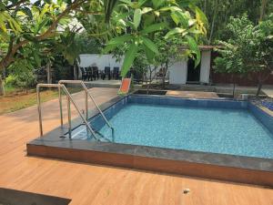 a swimming pool in a yard with a wooden floor at Siva Rama garden resort 6 AC Bed rooms ,swimming pool ,BoX cricket ,Born fair,BBQ, kichan&all, near beach road bheemilli vishakapatnam in Visakhapatnam