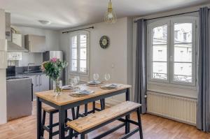 a kitchen with a wooden table with glasses and flowers at Le Duplex de l'Hôtel-de-Ville in Compiègne +24 photos