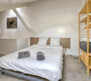 a bedroom with a large white bed with a hat on it at Le Duplex de l'Hôtel-de-Ville in Compiègne