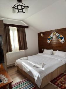 a bedroom with a large white bed and a window at Pensiunea Floare de Colt in Moisei