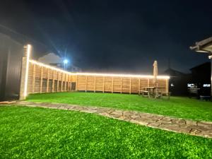 une cour arrière avec de l'herbe verte et une clôture la nuit dans l'établissement Jun resort 梅, à Kujukuri
