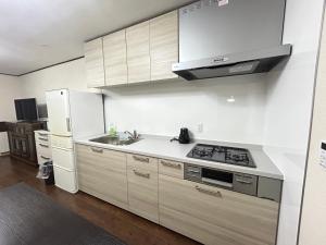 une cuisine avec des armoires blanches, un évier et un réfrigérateur dans l'établissement Jun resort 梅, à Kujukuri