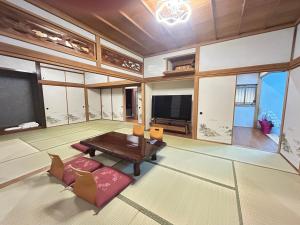 Il comprend un grand salon avec une table et une télévision. dans l'établissement Jun resort 梅, à Kujukuri