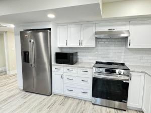 a kitchen with white cabinets and a stainless steel refrigerator at Annas Suites Rental in Bélanger