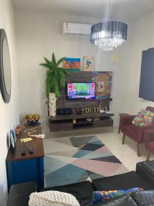 Una sala de estar con un televisor de pantalla plana en una pared. en The Greek house, en Itapemirim