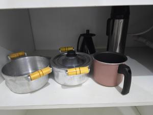 three pots and pans sitting on top of a counter at Flat completo a 5 minutos apé de mercado, farmácia in Aparecida de Goiania