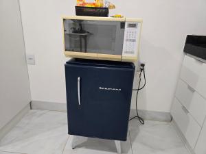 a microwave sitting on top of a blue refrigerator at Flat completo a 5 minutos apé de mercado, farmácia in Aparecida de Goiania