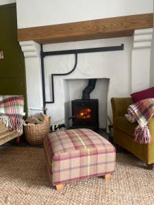 un salon avec une cheminée, une chaise et un pouf dans l'établissement Campbell's Cottage, à Blackwatertown