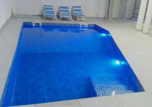 a large blue swimming pool with two blue chairs at La Villeneuvoise in Mbour