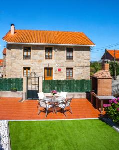 Un patio con una mesa y sillas frente a una casa. en Casa De Rama, en San Mamede de Carnota