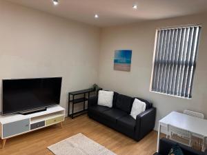 リバプールにあるByrom House Apartmentsの黒いソファと薄型テレビのあるリビングルーム