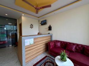 a living room with a red couch and a ceiling fan at Hotel Uday Palace in Rishīkesh