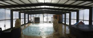 a room with a pool in a building with windows at Villa avec piscine privée en Normandie in Saint-Clair-dʼArcey