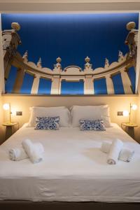Una gran cama blanca con paredes azules y almohadas. en Lolli Boutique & SPA Mondello, en Palermo