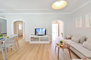 a white living room with a couch and a tv at Casa Nena by VillaGranCanaria in Playa del Ingles