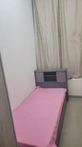 a small bed in a room with a pink sheet at Alfazan tower in Ajman 